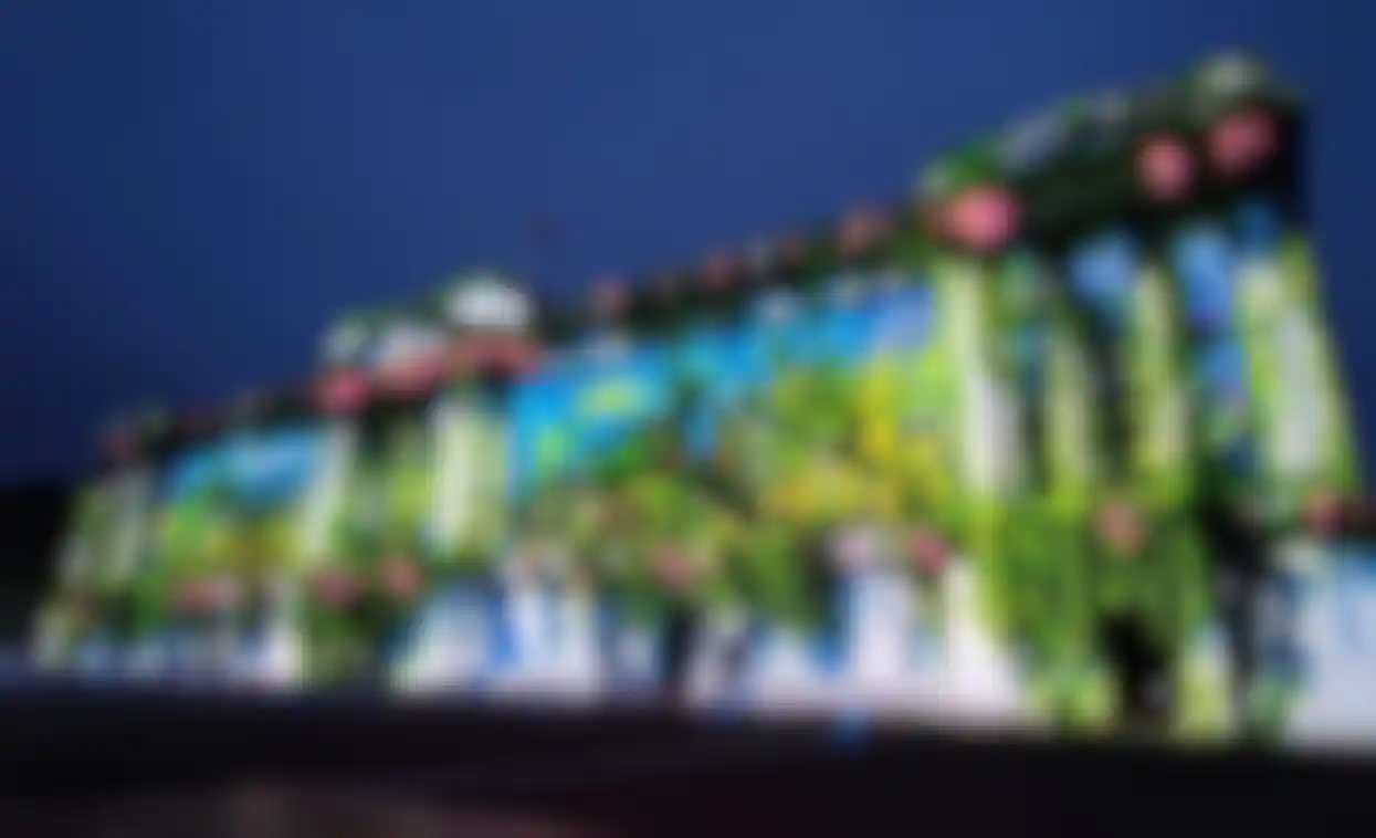 A 3D architectural rendering depicting digital art projected onto the exterior of a modern building, enhanced with dynamic lighting and visual effects, created using Redshift as the 3D rendering software.